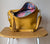 Yellow handbag with floral interior on a wooden stool against a plain background